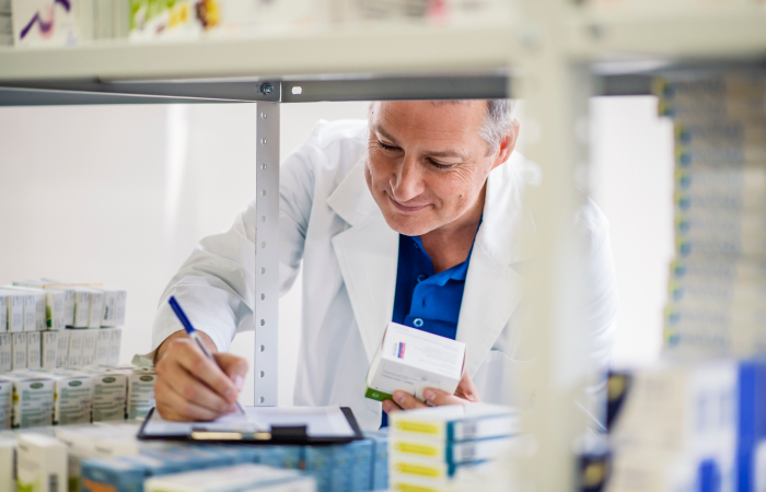 Pharmacist writing out prescription on pharmacy shelf