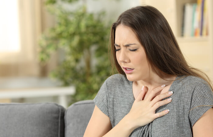 Young female holding her chest appearing to be in pain