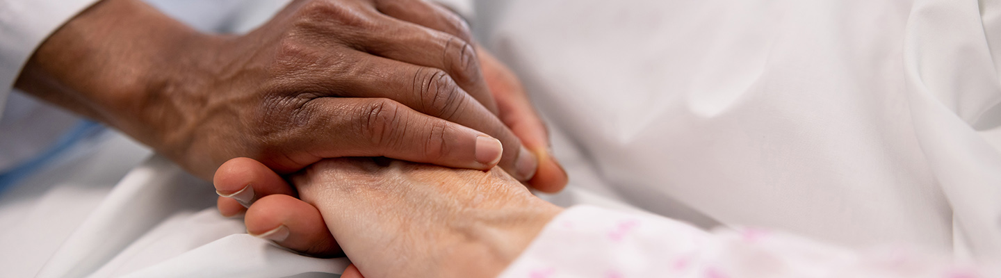 A close up of a care provider and patient holding hands