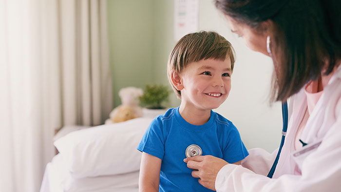 Female physician listening to the heart of a young boy