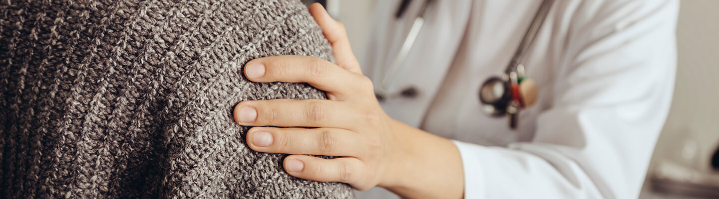 Doctor places a hand on a patient's shoulder