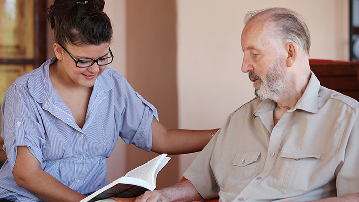 Young lady reading book to older man