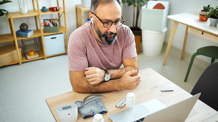 Man at computer with blood pressure cuff 