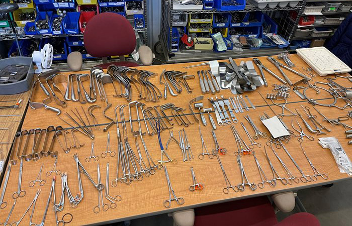 Surgical instruments are laid out on a table being prepped for distribution