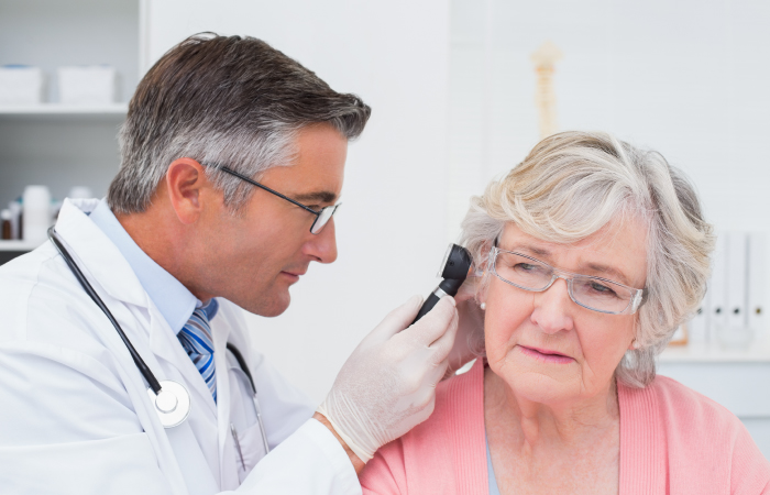 male doctor using a device to look at elderly woman's ear 