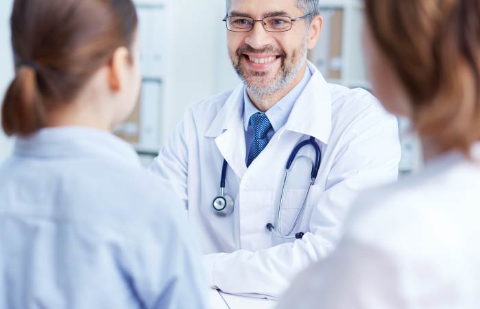 a male doctor with glasses checking in two female patients