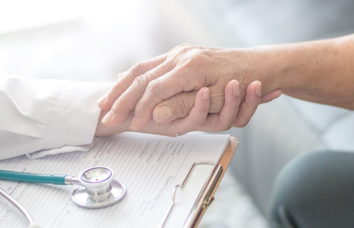 Doctor holding patient hand above medical records and a stethoscope