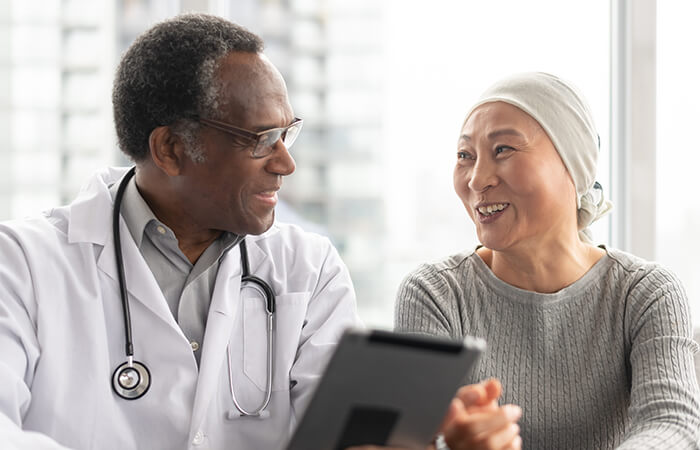 Black mature doctor going over results with mature Asian cancer patient