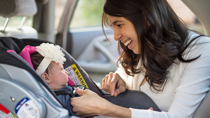 Mom putting baby girl into car seat