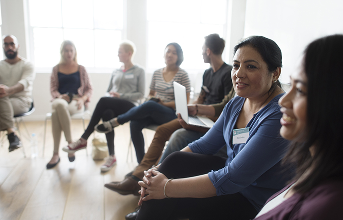 A group of men and women sit in a circle to discuss breastfeeding