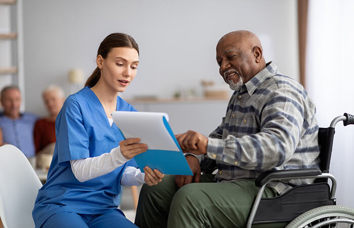 black man in a wheel chair going over chart with young white female nurse
