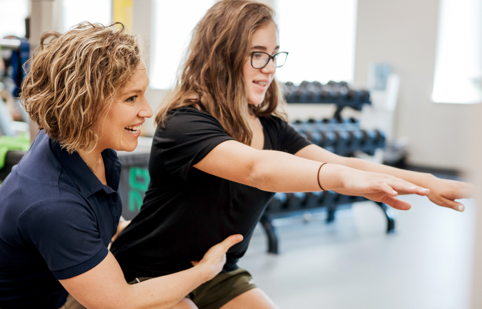 female nurse helping female patient with physical activity