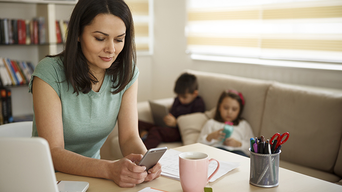 Woman at kitchen counter texting on phone