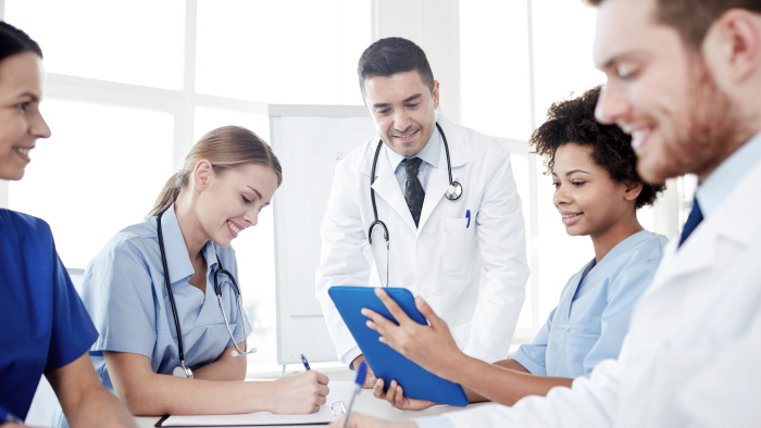 Five health care professionals gathered around conference table