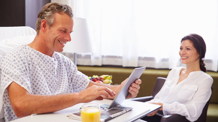 A patient is in bed with a loved one visiting