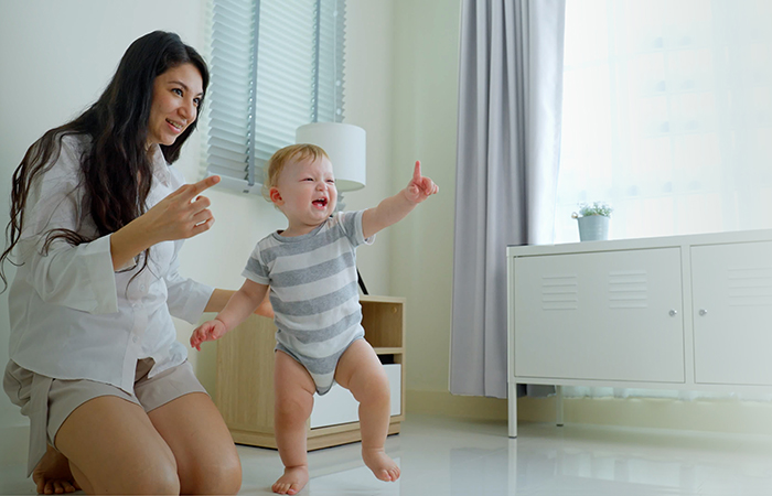 Young mom watching baby take first steps