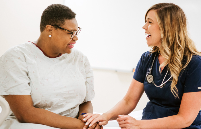 Photo of female patient and nurse smiling and holding hands