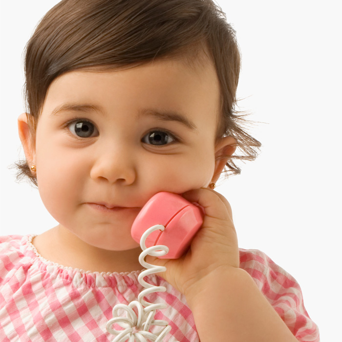 A baby girl talking on a play phone