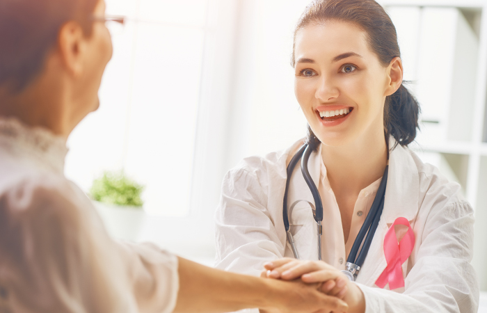 female nurse re-assuring older female patient by holding her hand