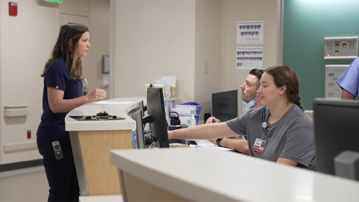 Anna talking with two colleagues at the nurses station