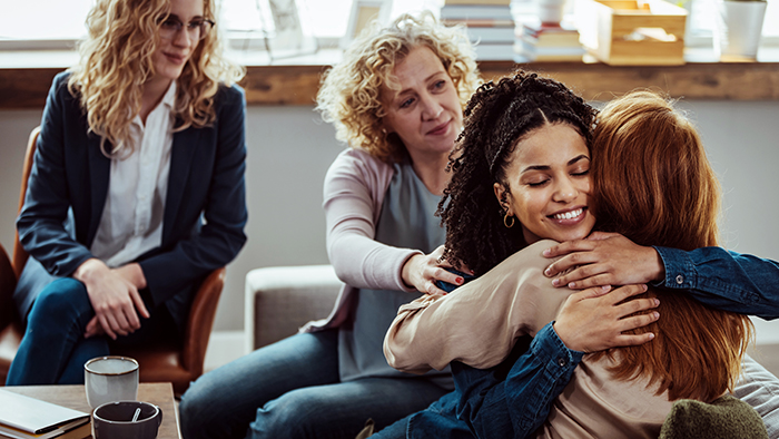 two women hugging in group of people