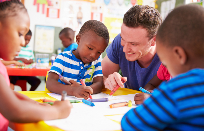 adult volunteer helping children with coloring projects