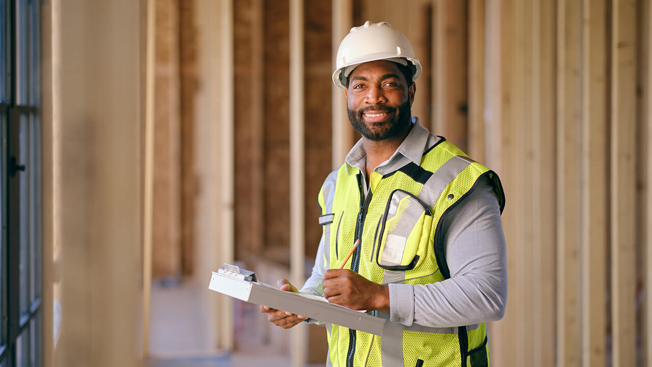 Young man wearing a hard had and reflective vest in a construction zone