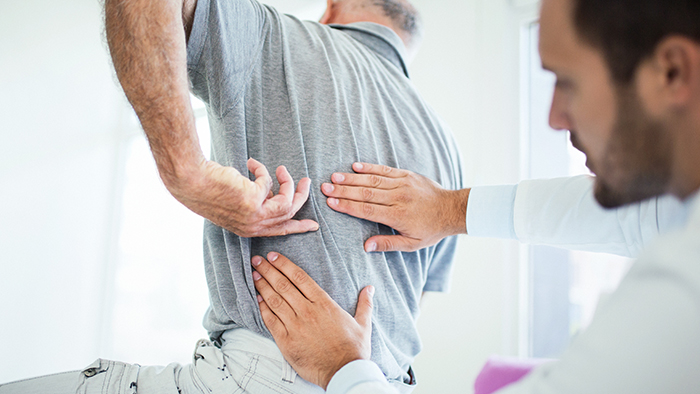 Male doctor evaluating man's back pain