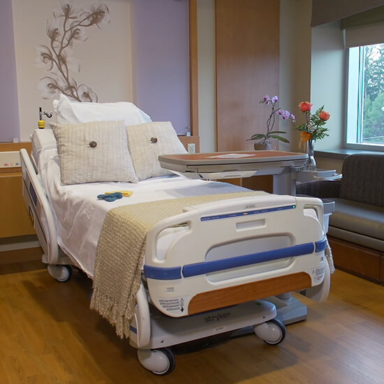 a hospital bed with decorative pillows on it in a hospital room 