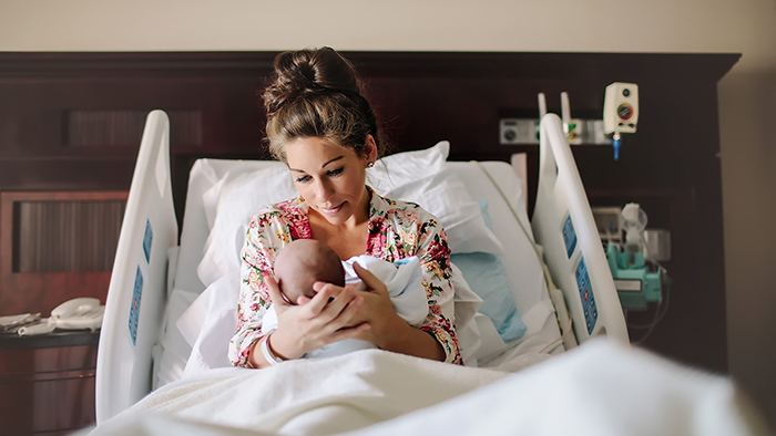 mother holding newborn baby in hospital bed