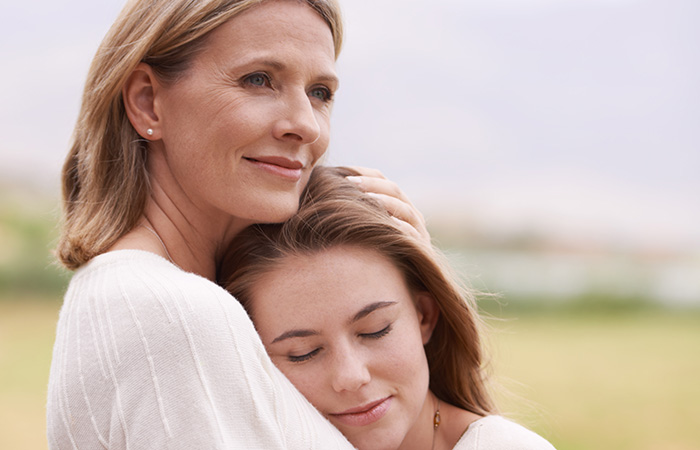 An older mother holds and comforts her daughter as she looks off into the distance