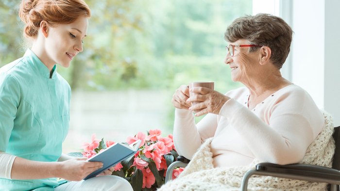 Young volunteer reading to senior woman patient