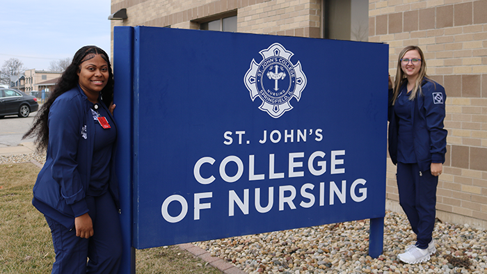St. John's College of Nursing Students standing next to the college sign