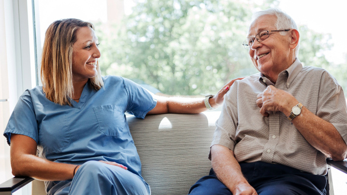 Young female nurse sitting talking with older gentlemen