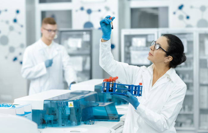 Laboratory scientist holding vials with red fluid in a laboratory