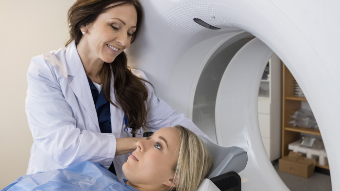 Woman CT technician helping young woman patient