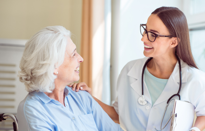 Female provider and elder patient smile and look at each other