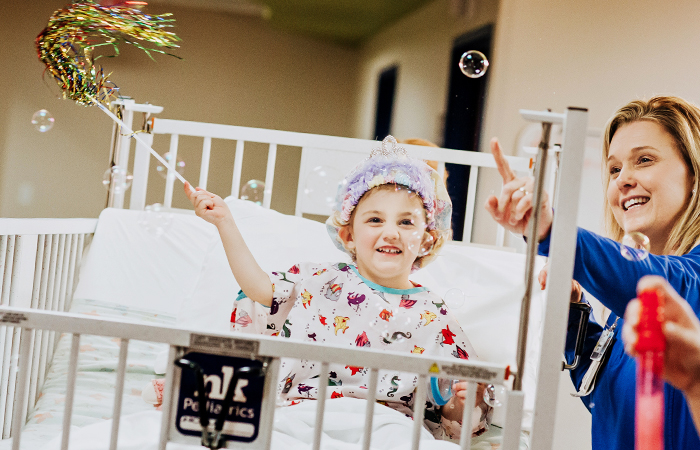 Female physician watching child in hospital use bubble wand