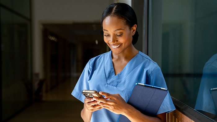 Young nurse filling out form on smart phone