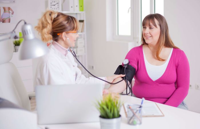 Female provider checking the blood pressure of a female patient wearing pink