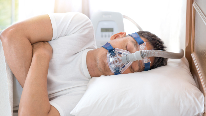 Man in bed with CPAP machine sleeping