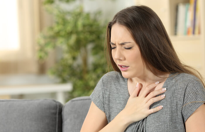 Female patient clutches her chest as she struggles to breathe
