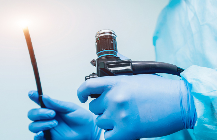 physician in scrubs holding colonoscopy camera