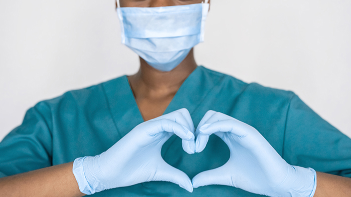 Female health care professional holding fingers in heart shape