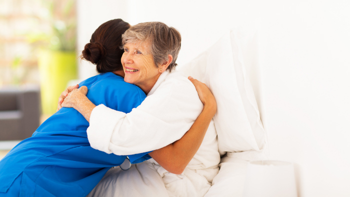 Young female nurse hugging female patient