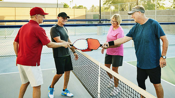 Two senior couples playing pickleball