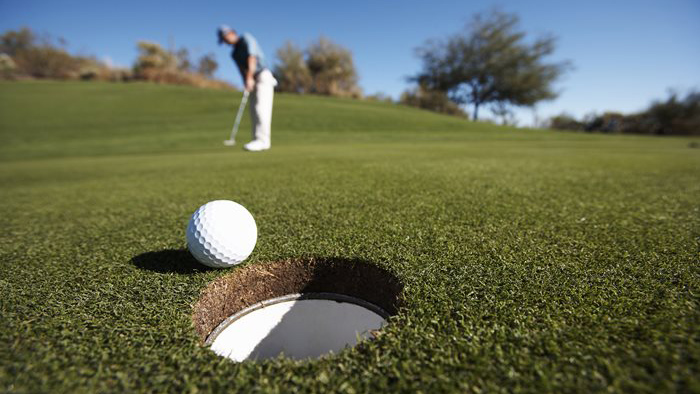 Golf ball on green about to drop in cup