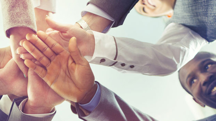 New hires putting hands together to show teamwork.
