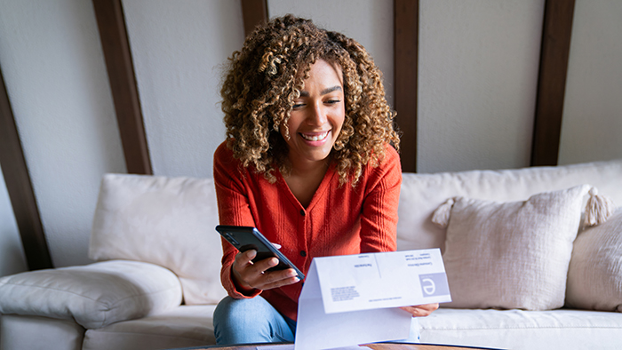 Young woman sitting on couch paying bills online