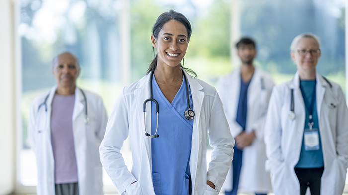 A female doctor stands in front of a group of doctors